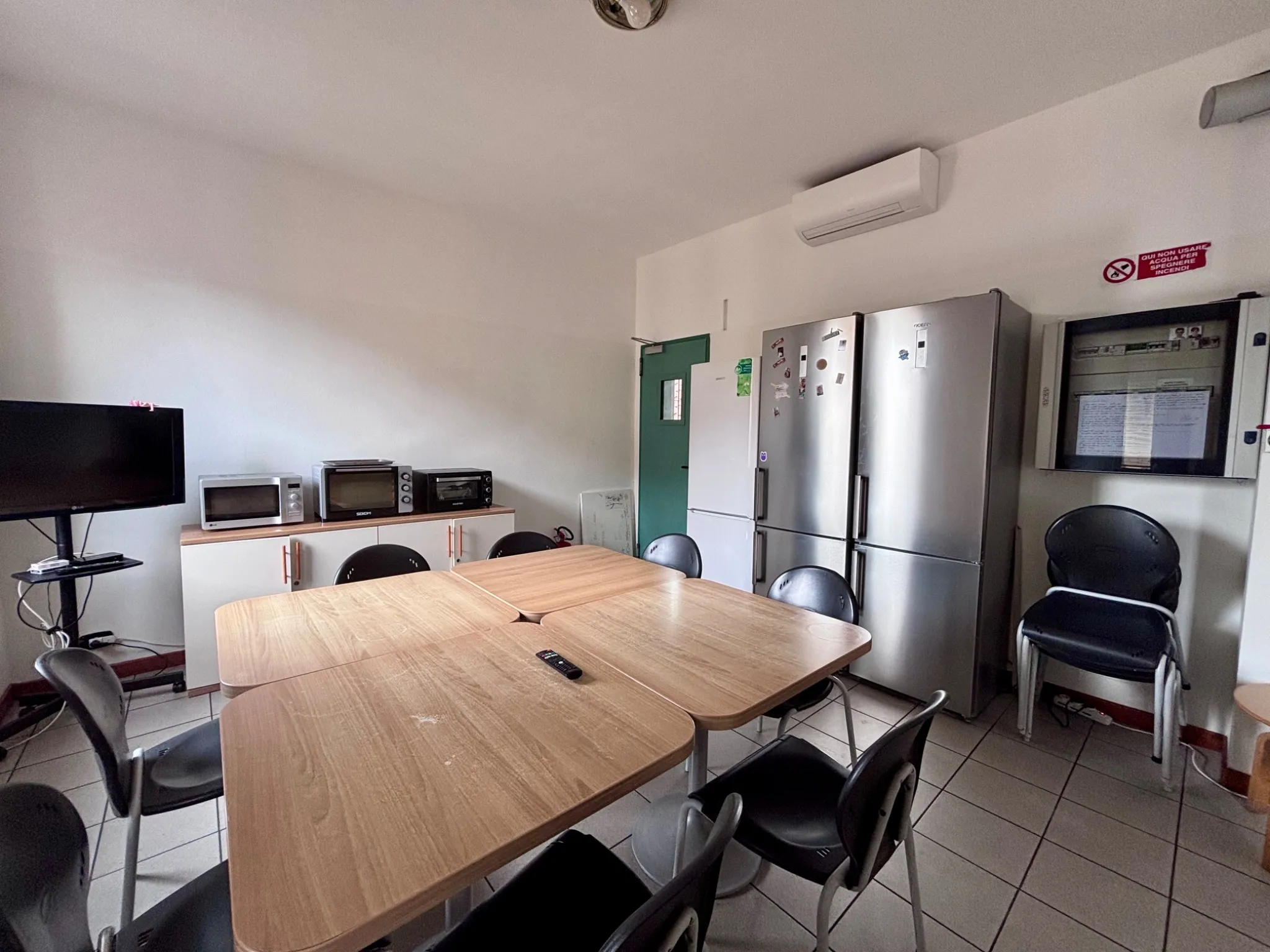 Cucina con tavolo, frigoriferi, microonde e televisore