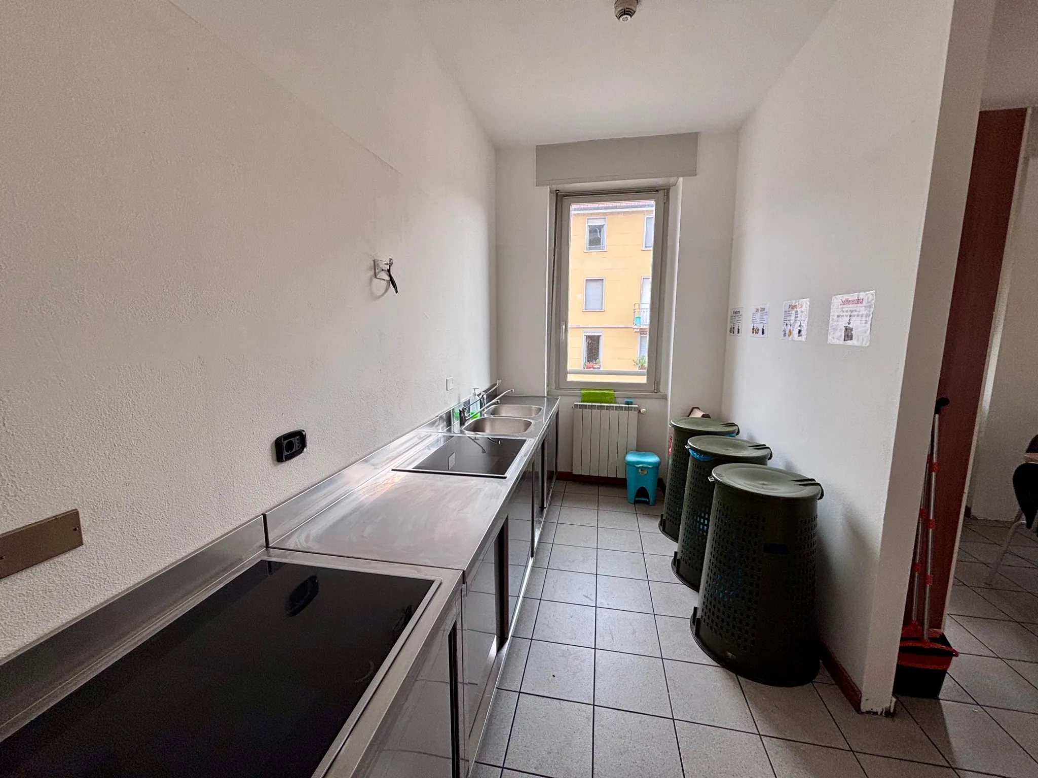 Area cottura con piani a induzione e cestini raccolta differenziata