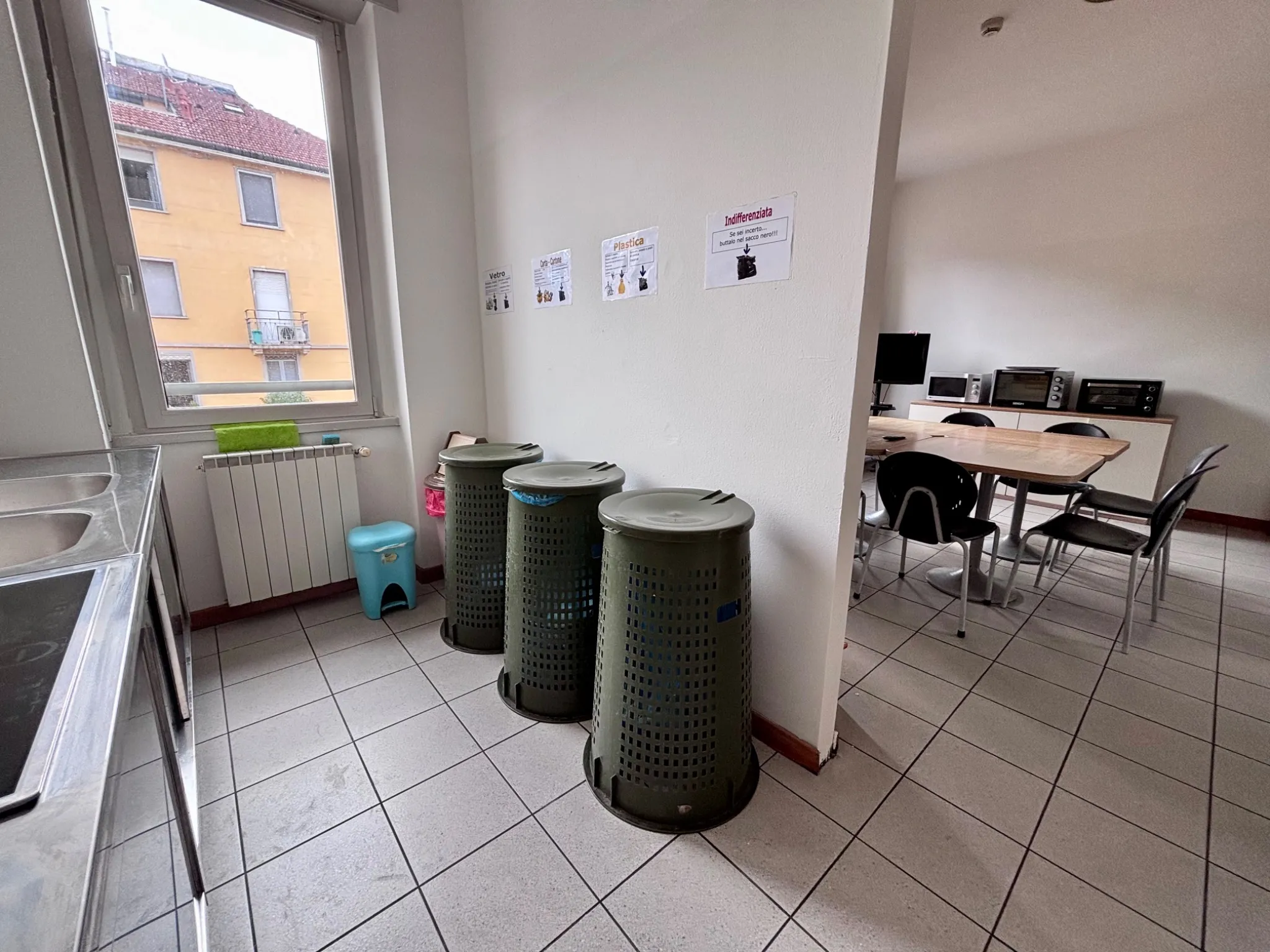 Cucina con cestini raccolta differenziata e area pranzo