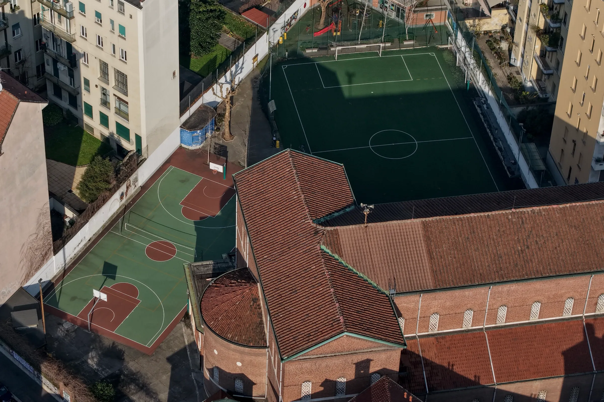 Vista aerea dei campi sportivi con campo da basket, campo da calcio e la chiesa del complesso